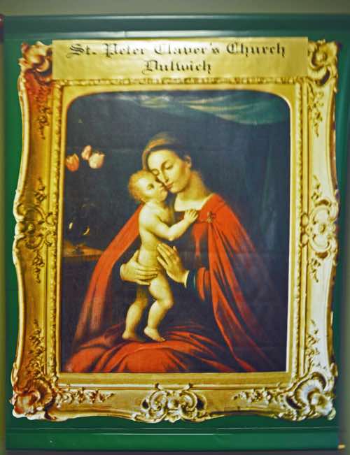 On the wall of the narthex is this unusual banner carrying a reproduction of a painting of Madonna and Child, set in a decorative gold frame.  There is no indication given of the artist.
