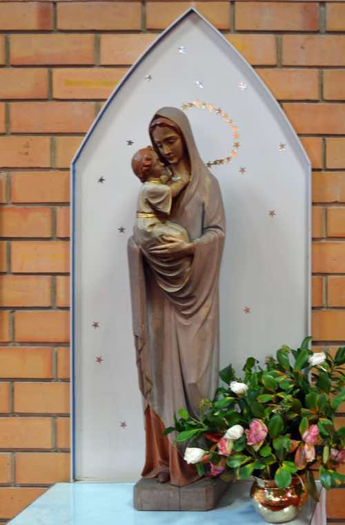 The shrine to the Virgin Mary shows Mary holding the Infant Jesus.  It is unusual in that Mary is not dressed in the customary blue.  She also has unusual footwear – a common protection against worshippers who reverently touch such statues.