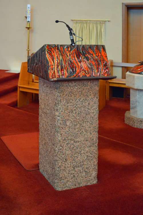 ‘Ambo’ is the official term for the pulpit in a Roman Catholic church.  Many churches have both a lectern (for reading the Scripture) and a pulpit (for preaching the Word).  The ambo serves both purposes here.