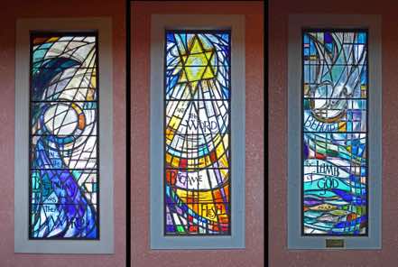 There are six North windows bearing the words (from the left): ‘In the beginning was the Word’, ‘And the Word became Flesh’, ‘Behold the Lamb of God’.  These windows were designed by Beverley Shore-Bennett.  [Click to ZOOM.]