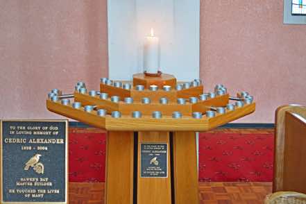 The candle stand was given in loving memory of Cedric Alexander 1926 – 2004, a Hawke’s Bay Master Builder.  The plaque features a tui, and carries the epitaph ‘He touched the lives of many’.  It was built by local craftsman Donald Alexander.  Lighting a candle is an aid to prayer.