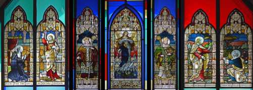 The stained glass inserts are beautiful.  Depicted here, from left: 
					• St Margaret Mary receives the vision of the Sacred Heart   • Bishop 
					• The Woman of the Apocalypse
					• Archbishop  • Christ gives Peter the keys to the Kingdom.  Each window, or pair of windows, is given in memory of parishioners of the earlier St Mary’s.  [Click photo to ZOOM IN]